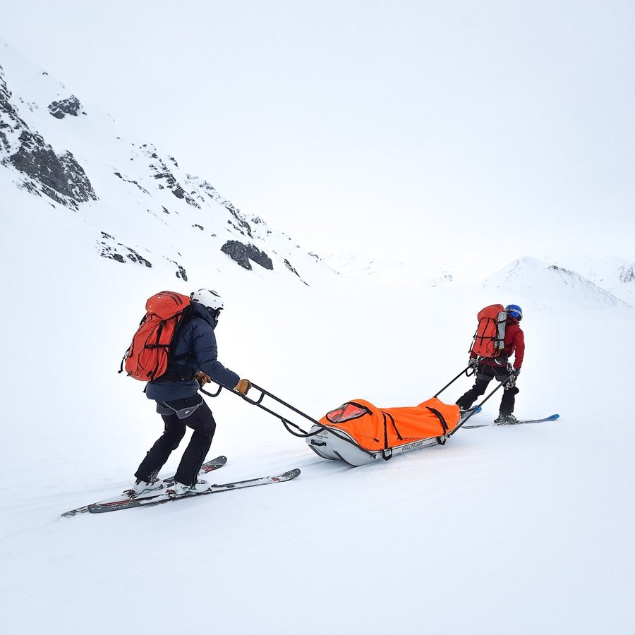 To redningsmannskaper på ski med pulk i vinterfjellet